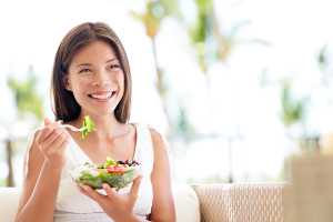 Healthy lifestyle woman eating salad smiling happy outdoors on b